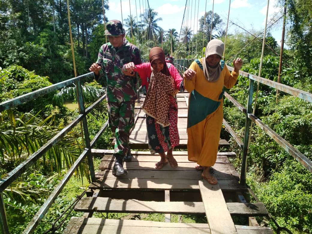 Jembatan Gantung Sedang Diperbaiki, Serka Rohman dengan Respek dan Santun Bantu Nenek Nenek Melintas