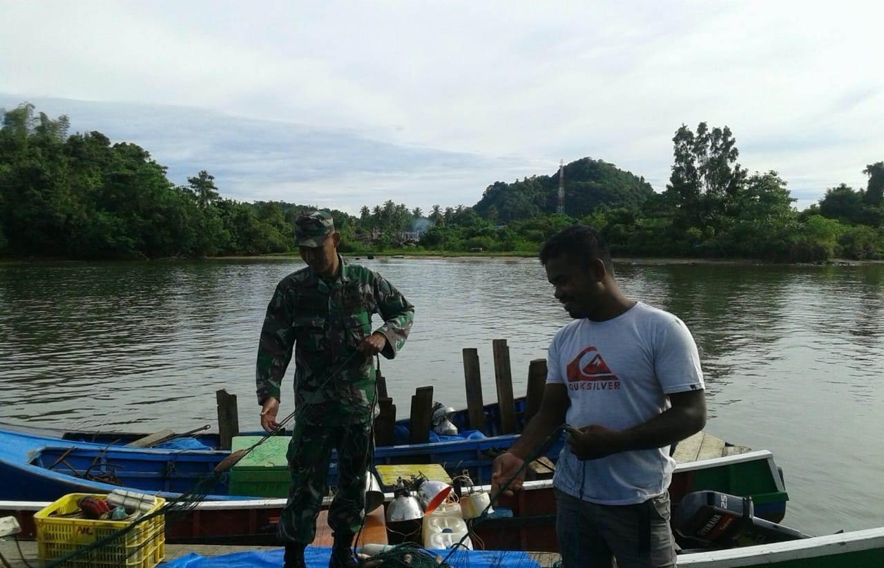 Sertu Sigit Bantu Nelayan Bersihkan Jaring Ikan