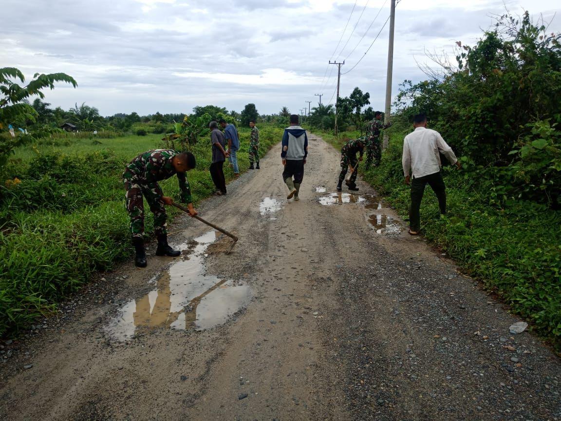 Anggota Kompi Senapan D Bantu Warga Timbun Jalan Berlubang