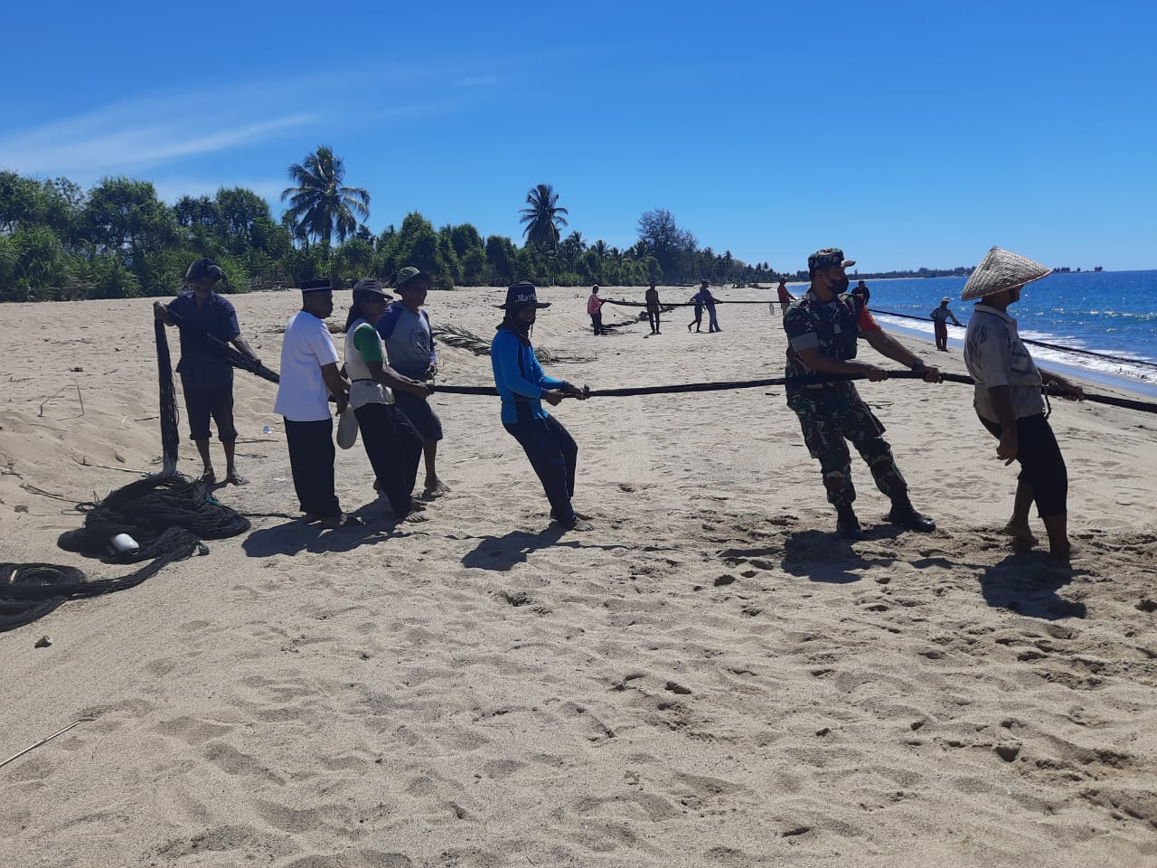 Babinsa Dan Nelayan Kompak Bantu Dalam Menarik Pukat Ikan Di Pantai
