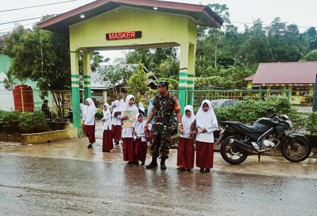 Kepedulian Serda Suharianto Bantu Anak SD Seberangi Jalan Raya