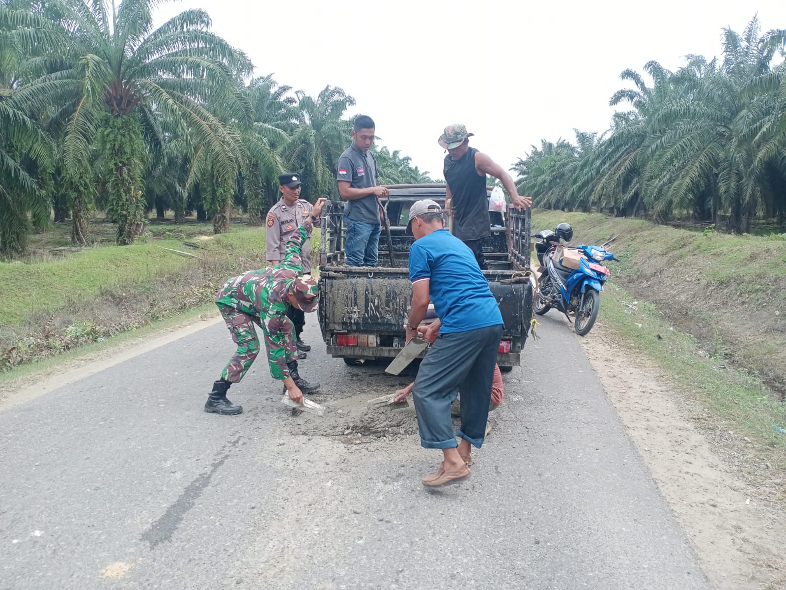 Anggota Koramil 04/Bendahara Gotong-Royong Bersama Masyarakat Tambal Jalan Berlubang