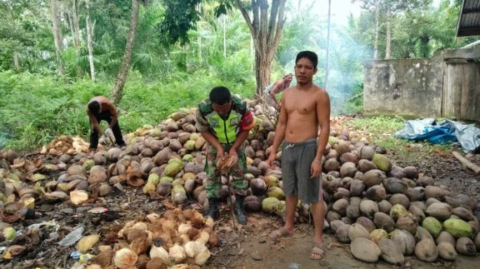 Sambangi Warga Binaan, Babinsa Bantu Kupas Kelapa Tua untuk Dijadikan Kopra