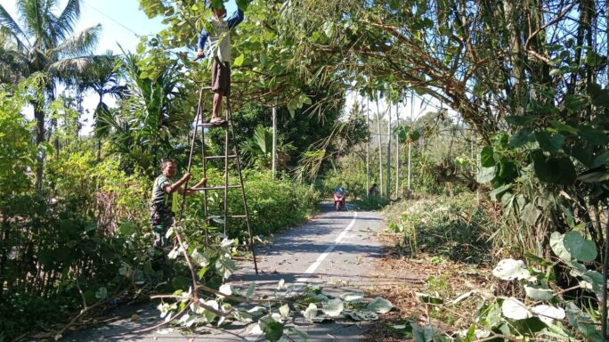 Babinsa Ajak Warga Gotong Royong Pangkas Pohon Yang Menutupi Jalan