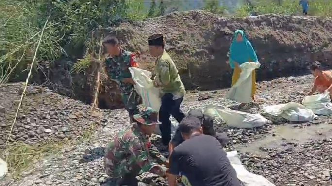 Babinsa Ajak Warga Gotong Royong Bangun Tanggul Darurat Dari Goni Guna Antisipasi Banjir Saat Hujan.