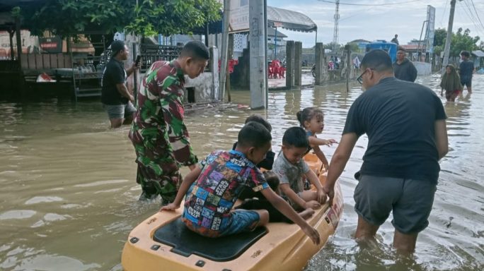 Babinsa Koramil 21/Kota Sigli bantu evakuasi warga korban banjir.