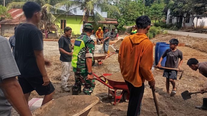 Penuh Semangat, Babinsa Bersama Warga Gotong Royong Dalam Pengecoran Lapangan Voli