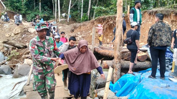 Personel Satgas Penanggulangan Bencana Bantu Penyebrangan Anak-Anak Dan Lansia Di Jembatan Darurat Umah Besi